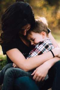 A mom hugging her upset son.